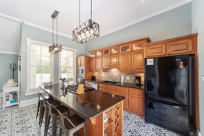 A kitchen with wooden cabinets, a black refrigerator, and a bar area with stools. - Private historic district apt with pool-suite A (Ocala)