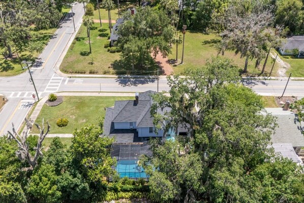 A residential property with a swimming pool, surrounded by lush greenery and a road. - Private historic district apt with pool-suite A (Ocala)