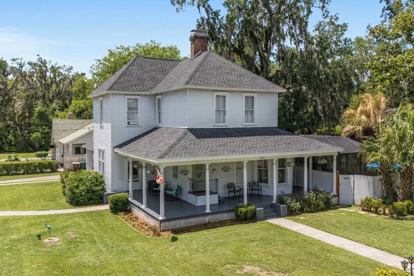 A two-story house with a covered porch and a well-maintained lawn. - Private historic district apt with pool-suite A (Ocala)