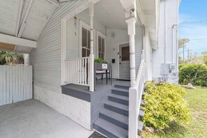 A house with a covered porch, a front door, and a staircase leading to the entrance.