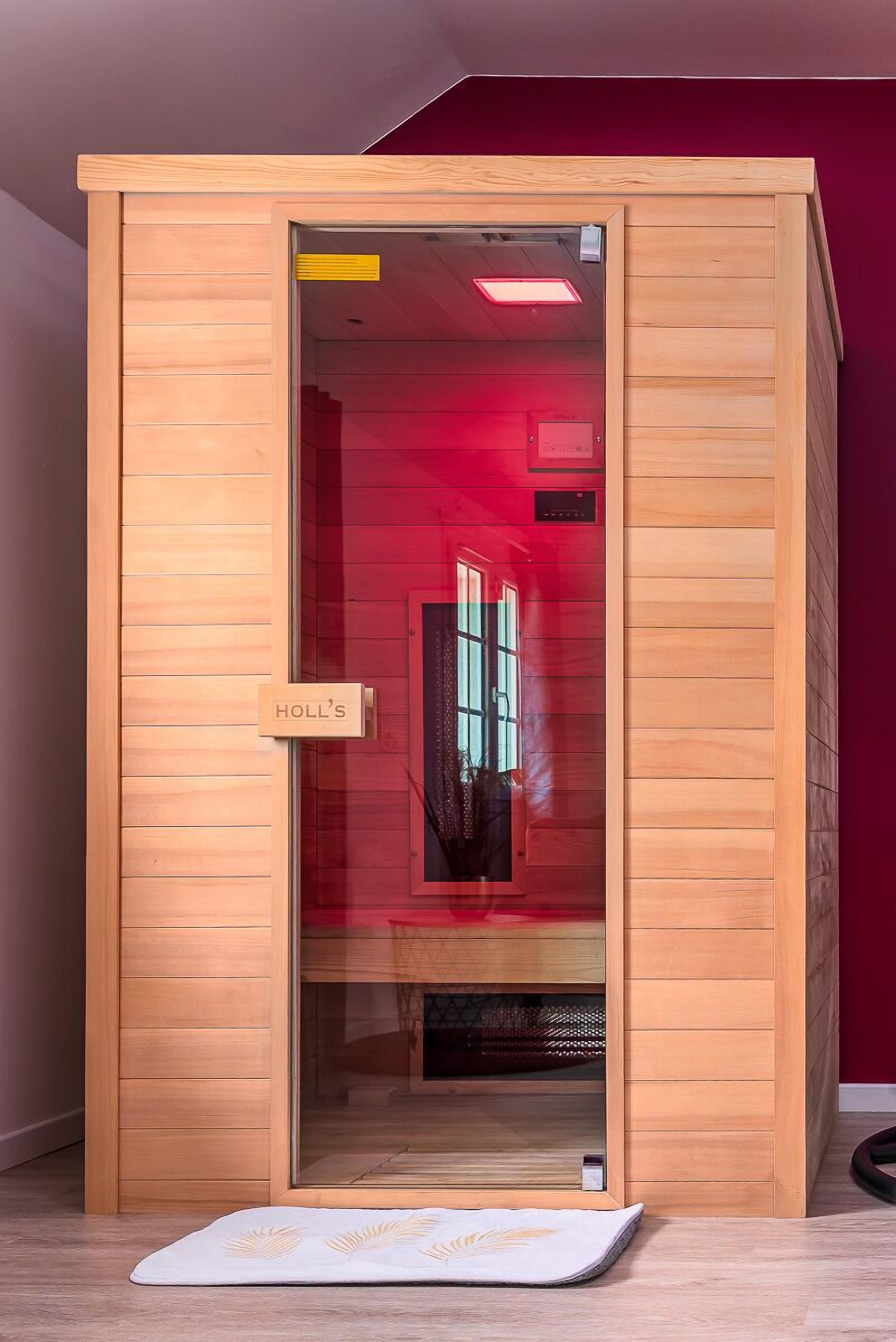 Un sauna en bois doté d’une porte en verre, d’un panneau de commande visible et d’une plaque signalétique portant l’inscription « HOLL’S ».