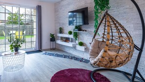 A modern living room with a hanging chair, a flat-screen TV, and a fireplace. - Suite L'échappée - Romantic home - Private SPA (PEZARCHES)