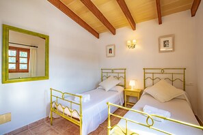 Une chambre avec deux lits, un plafond en bois, un miroir et deux lampes fixées au mur.
