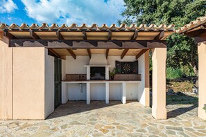 An outdoor kitchen area with a stone floor, a tiled roof, and a view of the surrounding landscape. - Lovely villa in Pollensa countryside (Pollensa / Pollença)
