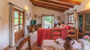 A cozy room with a dining table set for two, wooden beams on the ceiling, and a red sofa. - Lovely villa in Pollensa countryside (Pollensa / Pollença)