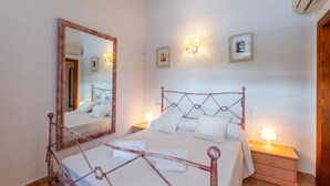 A bedroom with a metal-framed bed, bedside tables with lamps, a large mirror, and a wall-mounted light fixture.