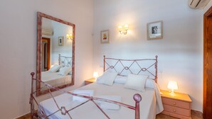 A bedroom with a metal-framed bed, bedside tables with lamps, a large mirror, and a wall-mounted light fixture. - Lovely villa in Pollensa countryside (Pollensa / Pollença)