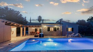 A swimming pool with stone tiles, a covered patio with outdoor furniture, and a stone building with a stone facade. - Lovely villa in Pollensa countryside (Pollensa / Pollença)
