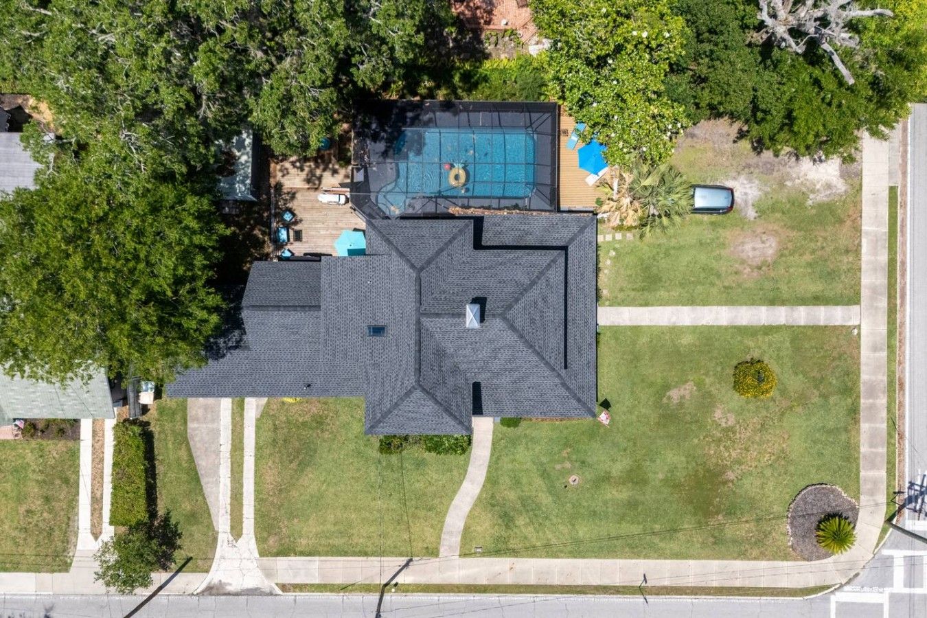 A residential property with a large, dark-colored roof, a swimming pool, and a well-maintained lawn.