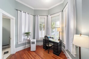 A corner room with a desk, chair, lamp, air conditioner, and a potted plant. - Private historic district apt with pool-suite B (Ocala)