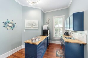 A compact kitchen with a wooden countertop, a microwave, and cabinets. - Martin House | Historic Suite with Pool Downtown (Ocala)