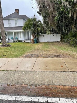 A residential property with a front yard, a white fence, and a house with a porch. - Martin House | Historic Suite with Pool Downtown (Ocala)