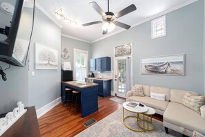 A compact living space with a kitchenette, a dining area, and a seating area with a sofa and a coffee table. - Martin House | Historic Suite with Pool Downtown (Ocala)