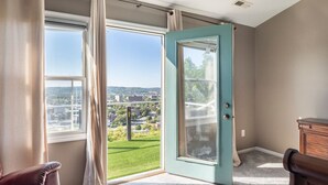 Ein Zimmer mit einer großen Schiebeglasdoor, einem braunen Ledersessel und einem hölzernen Schminktisch.