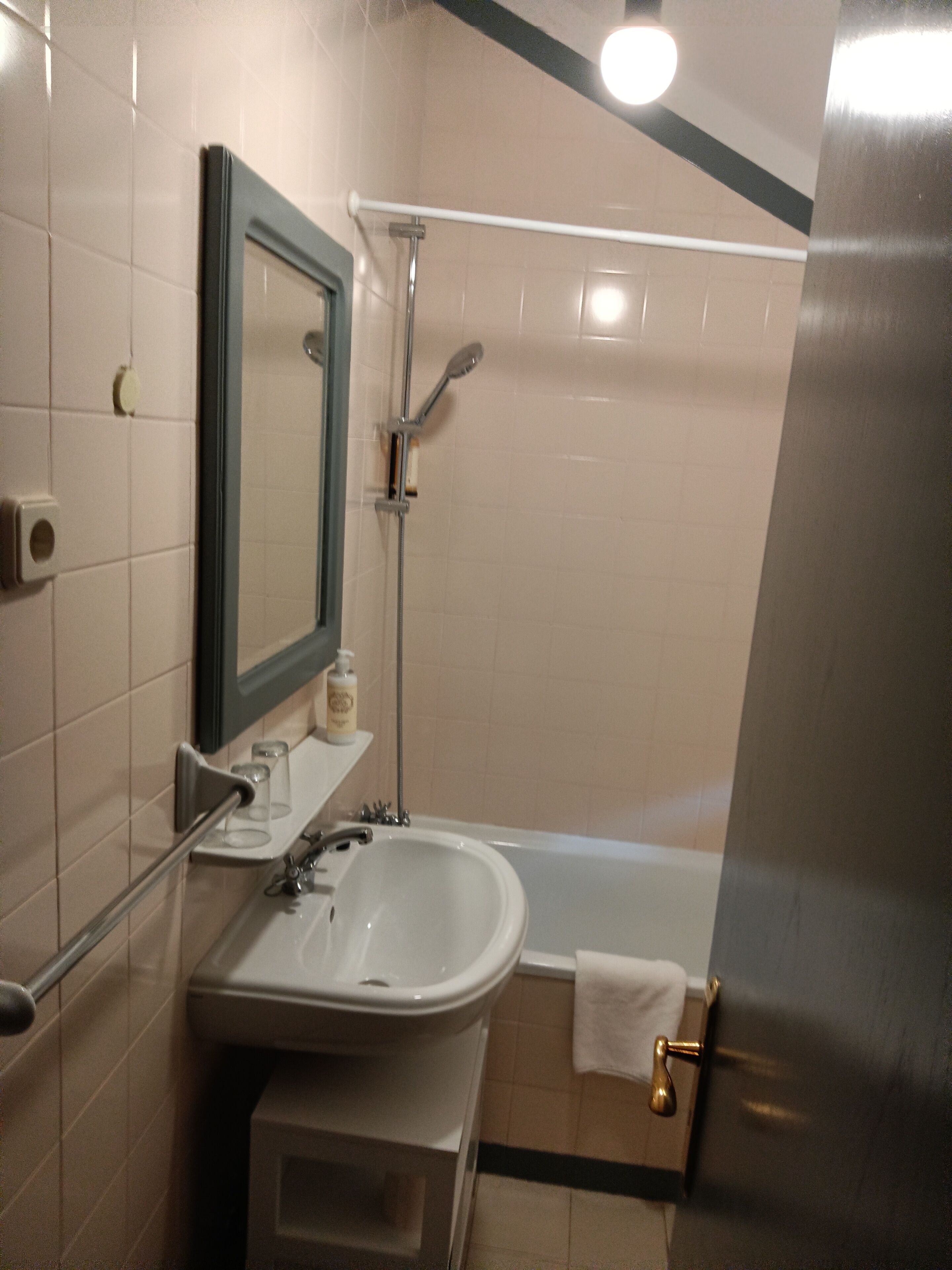 A bathroom with a sink, mirror, and shower.