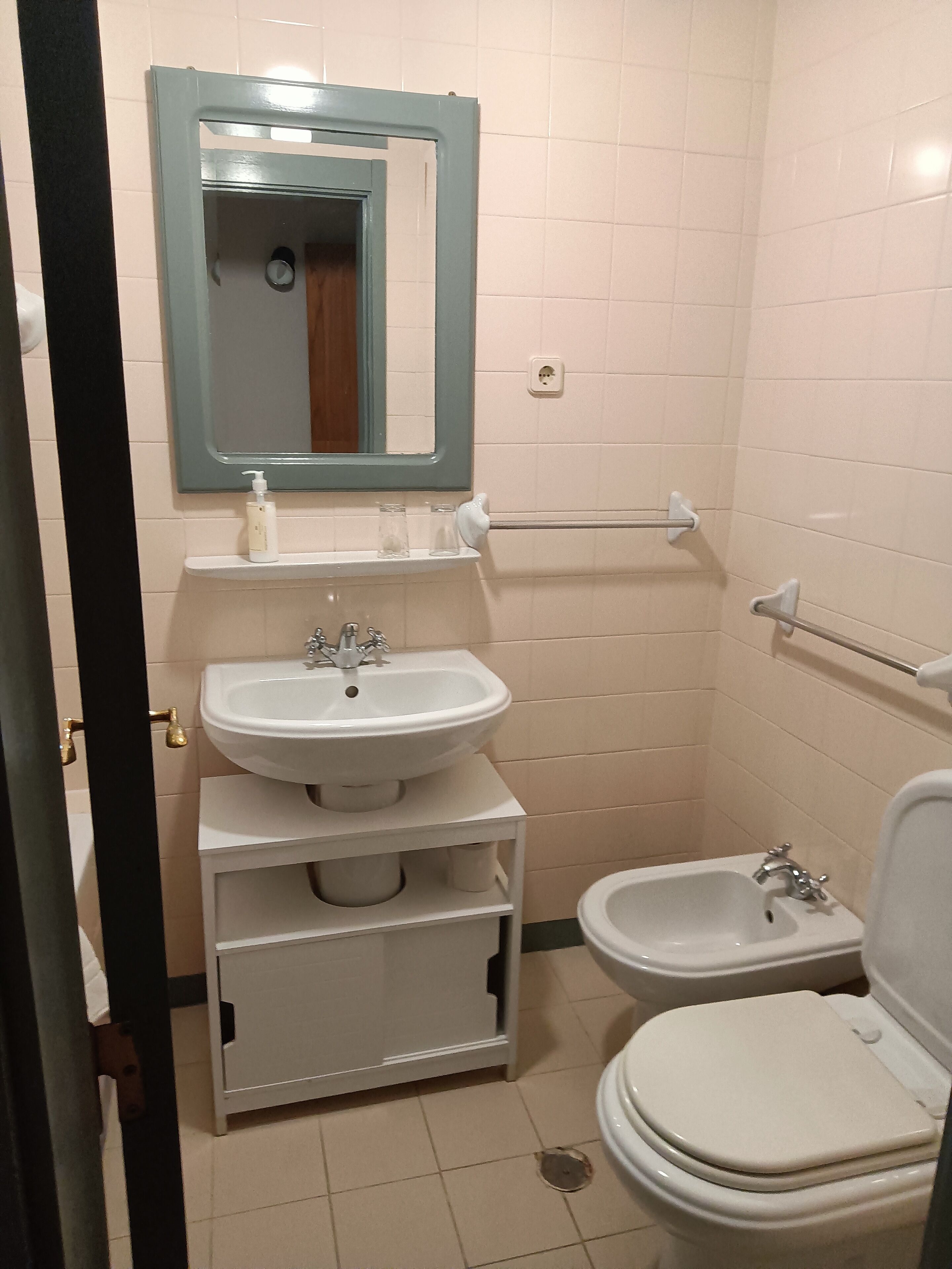 A small, clean bathroom with a sink, mirror, and toilet.
