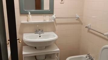 A small, clean bathroom with a sink, mirror, and toilet.
