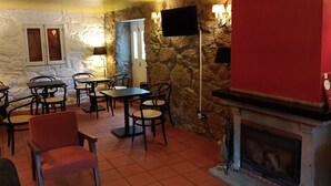 A cozy room with stone walls, a fireplace, and a television mounted on the wall. - Quinta de Leandres (Manteigas)