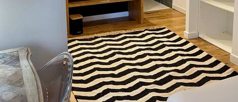 A modern bathroom with a wooden vanity, two sinks, a mirror, and a black and white striped rug.