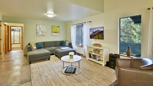 Ein Wohnzimmer mit Ecksofa, Couchtisch, Fernseher und Bücherregal.