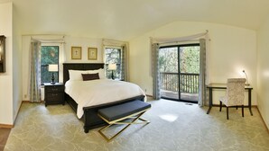 Ein Schlafzimmer mit Bett, Nachttischen, einem Sessel und einem Balkon.