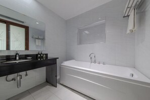 Une salle de bain moderne avec une grande baignoire, un meuble-lavabo foncé et un miroir avec un cadre en bois.