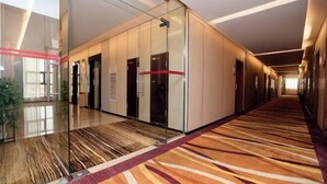 A modern hotel corridor with glass doors, a patterned carpet, and a long hallway. - Meicheng Huatian Holiday Hotel (Anhua)