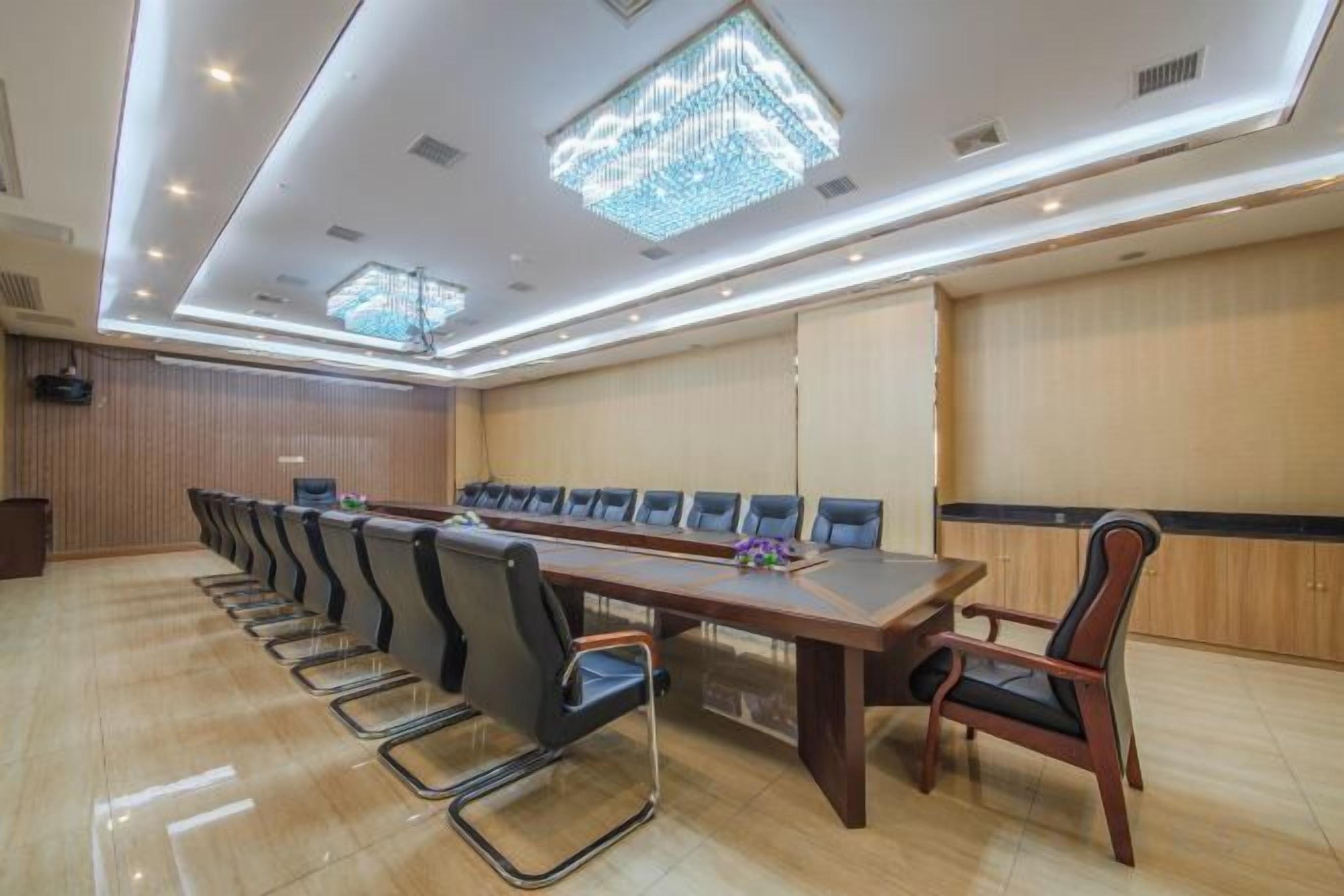 Un salón de conferencias con una larga mesa y sillas, un atril y una araña.
