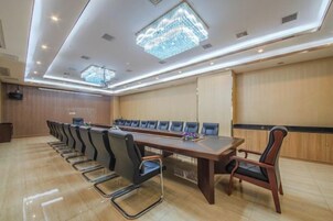 Un salón de conferencias con una larga mesa y sillas, un atril y una araña.
