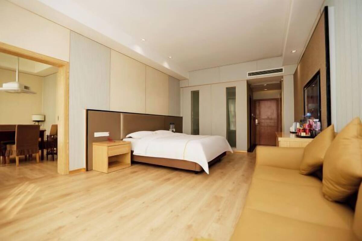 Une chambre d’hôtel avec un grand lit, un canapé, un bureau avec une chaise et un miroir.