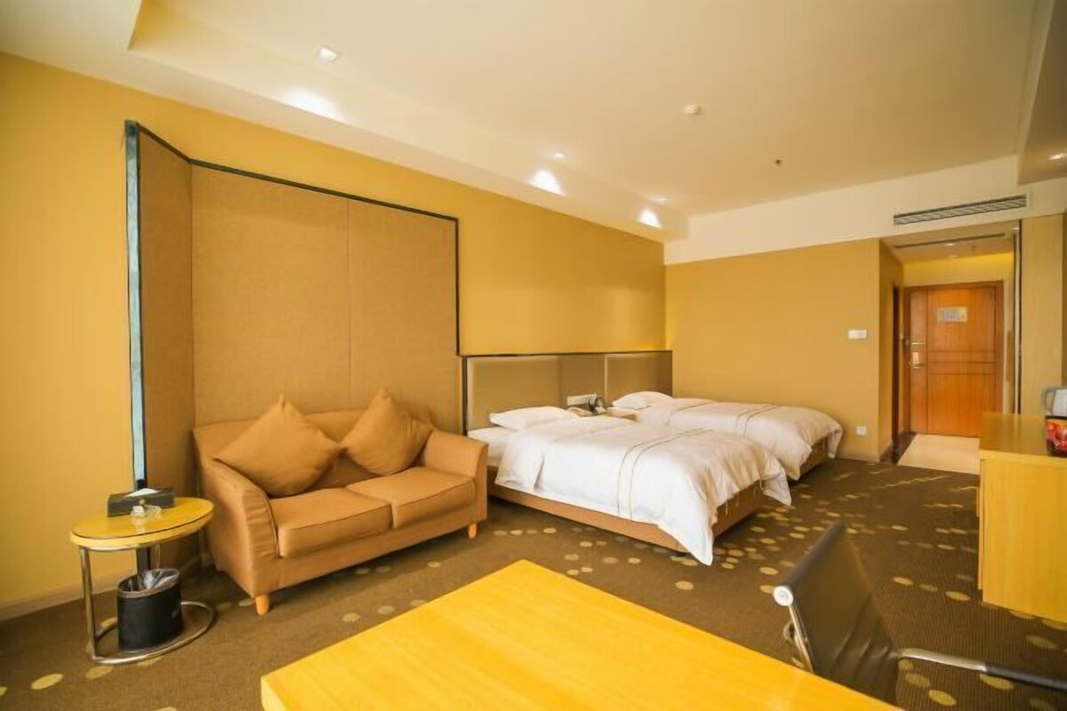 Une chambre d’hôtel avec un lit, un canapé, une petite table et un bureau.