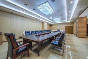 Une salle de conférence avec une longue table, des chaises et un lustre.