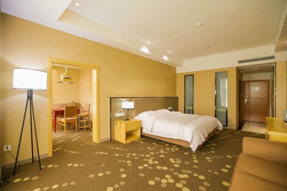 Une chambre d’hôtel comprenant un lit, une table de chevet, une lampe et un bureau avec une chaise.