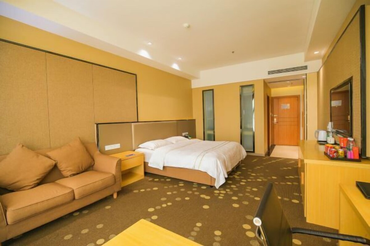 Une chambre d’hôtel avec un lit, un canapé, un bureau et un miroir.