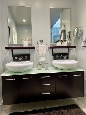 A modern bathroom with two white sinks, a dark vanity, and large mirrors.