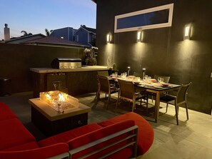 A patio with a fire pit, dining table, and chairs.