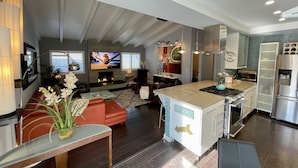 A modern kitchen with a central island, built-in appliances, and a dining area with a red sofa. - Modern Beach Bungalow, walk to beach, family and dog friendly (Oxnard)