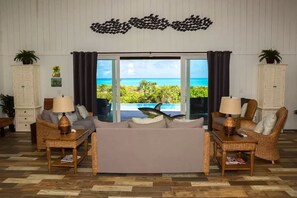 Ett vardagsrum med en soffa, två fåtöljer, ett soffbord och utsikt över havet.