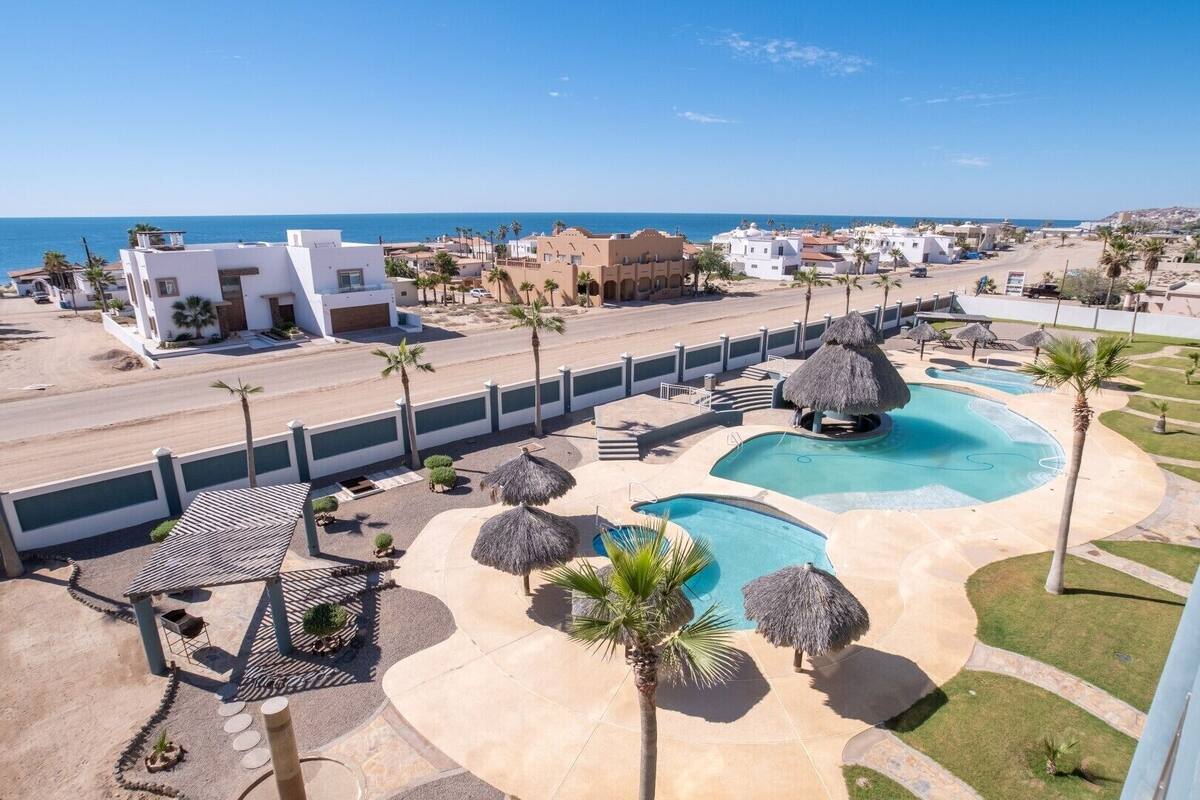 A resort with multiple swimming pools, a beach, and a view of the sea.