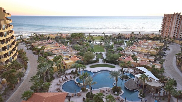 A resort with multiple swimming pools, palm trees, and beachfront views. - RPB Property Management (Puerto Peñasco)