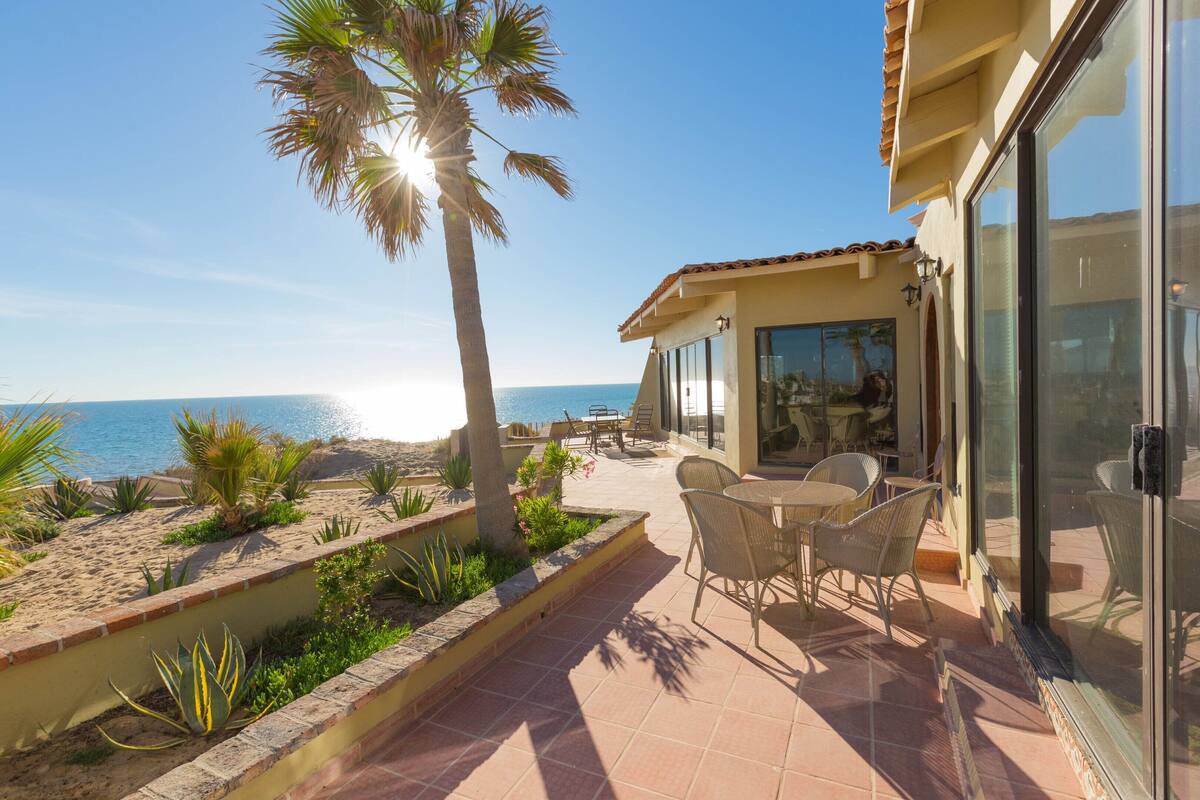 A patio with outdoor furniture, a palm tree, and a view of the ocean.