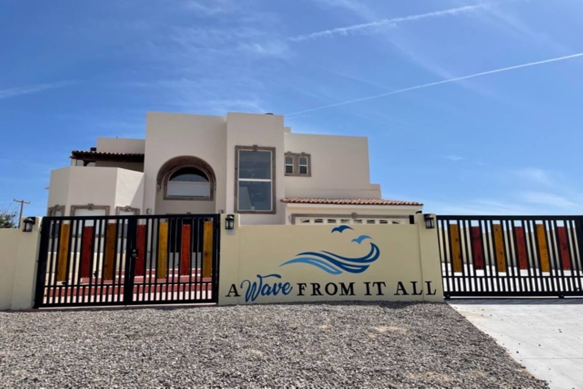 A building with a beige facade, a black gate, and a sign that reads "A Wave from It All".
