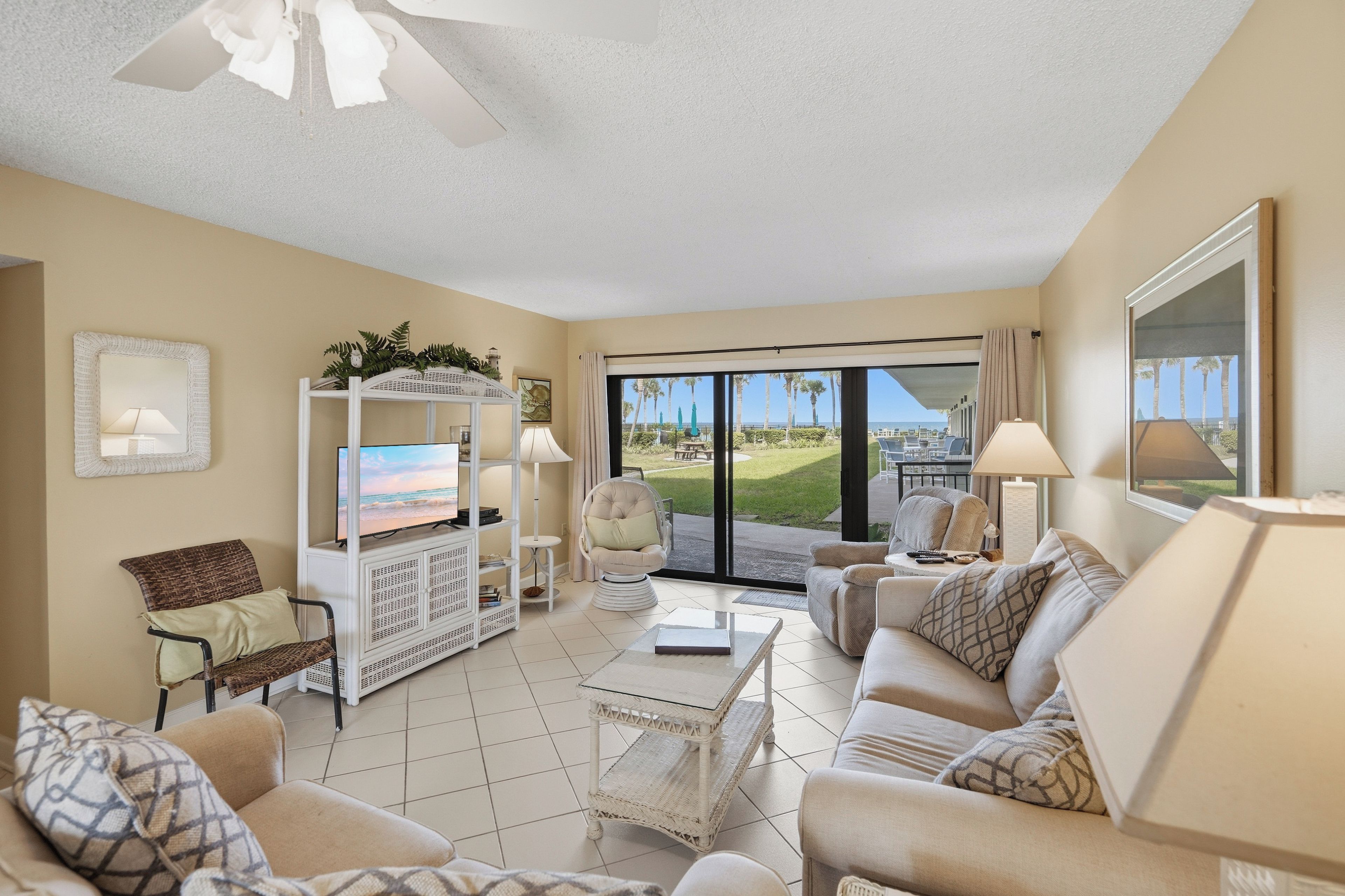 A spacious living room with a large TV, comfortable seating, and a view of the outdoors.