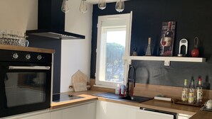 Una cocina moderna con horno empotrado, encimera de madera y ventana con vistas a zonas verdes.