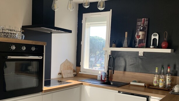 Een moderne keuken met een ingebouwde oven, een houten aanrecht en een raam met uitzicht op groen.