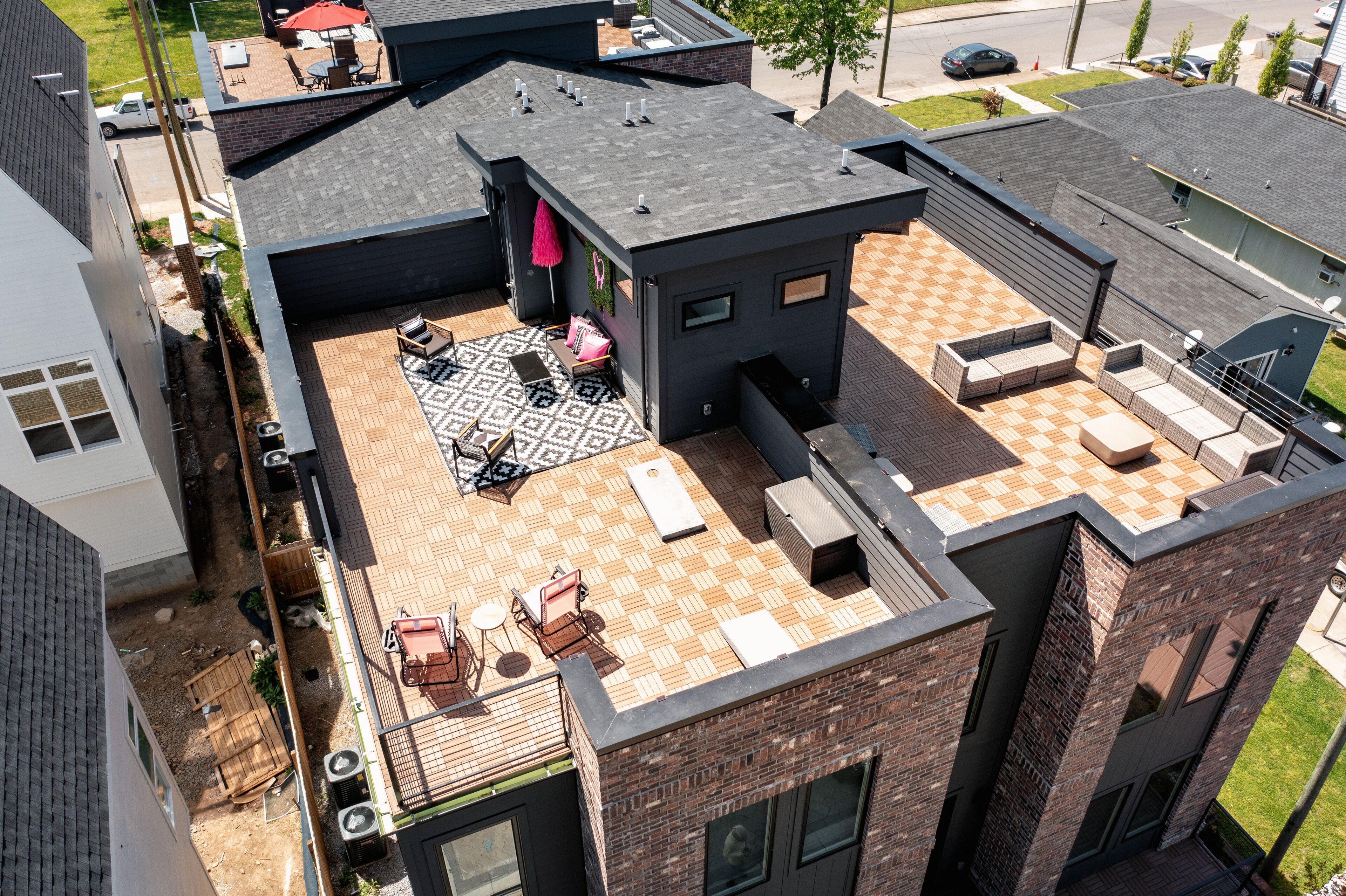 Una terraza en la azotea con mobiliario exterior, alfombra estampada y un pequeño jardín.