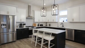 Uma cozinha moderna com uma ilha central, eletrodomésticos de aço inoxidável e iluminação pendente.