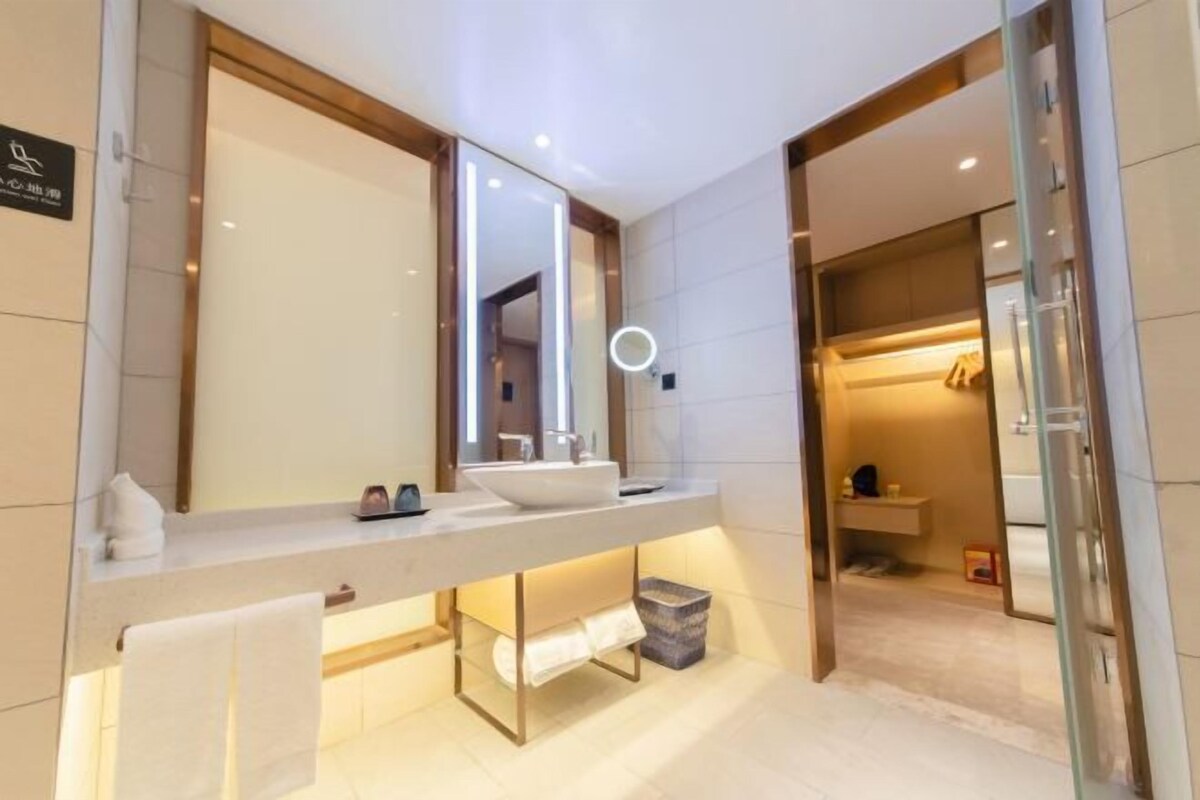 Uma casa de banho moderna com um espelho grande, uma pia e um porta-toalhas.