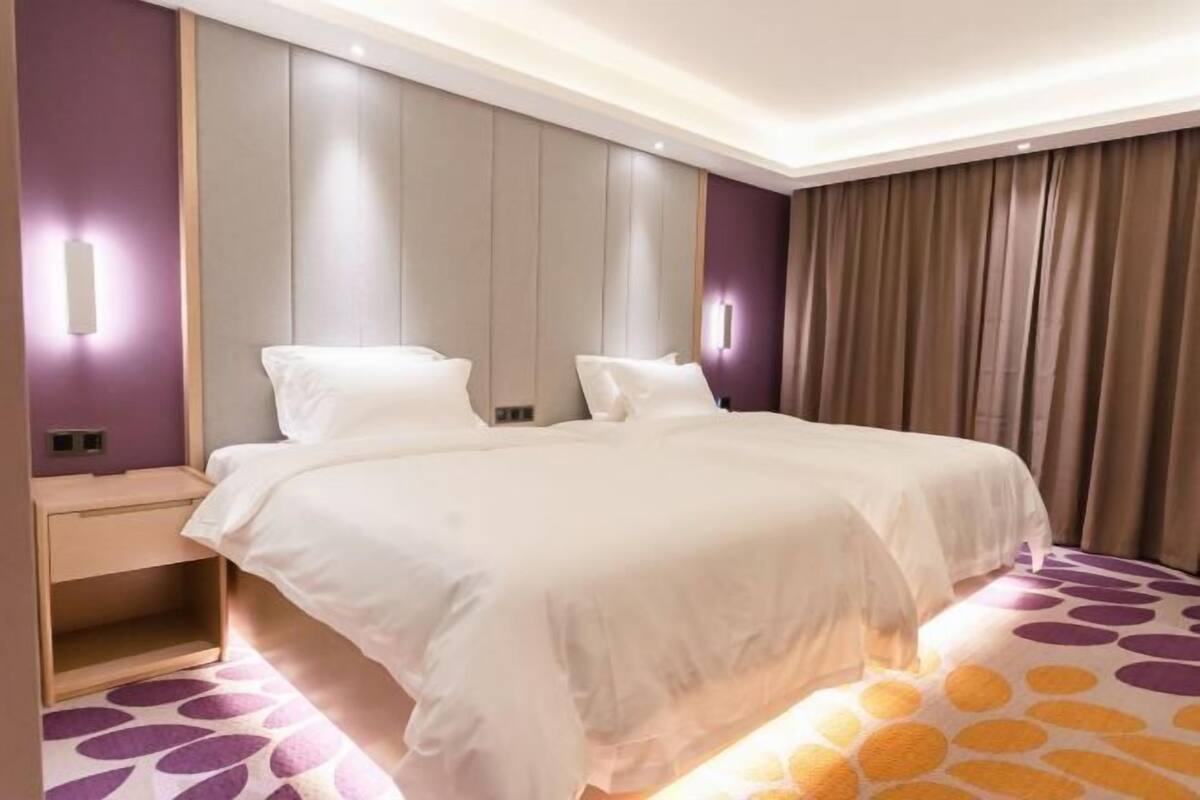 A double bed with white bedding, a nightstand, and a wall-mounted light fixture.