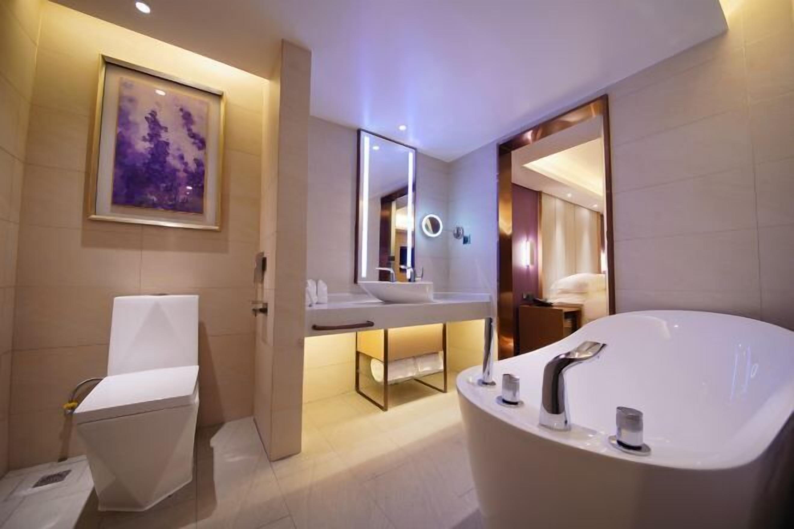 Un baño moderno con una bañera independiente, un tocador con espejo y un inodoro.